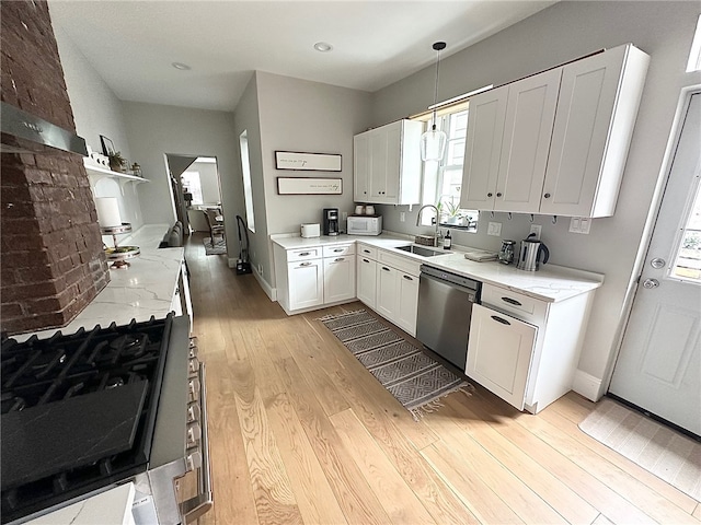 kitchen featuring stainless steel dishwasher, sink, white cabinetry, and decorative light fixtures