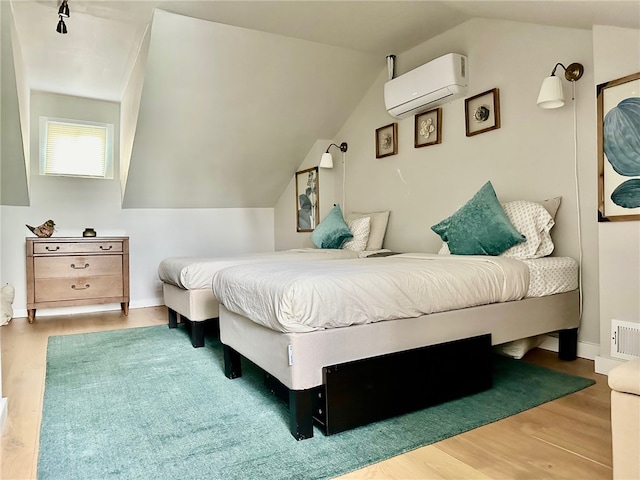 bedroom featuring vaulted ceiling, a wall mounted AC, and wood-type flooring