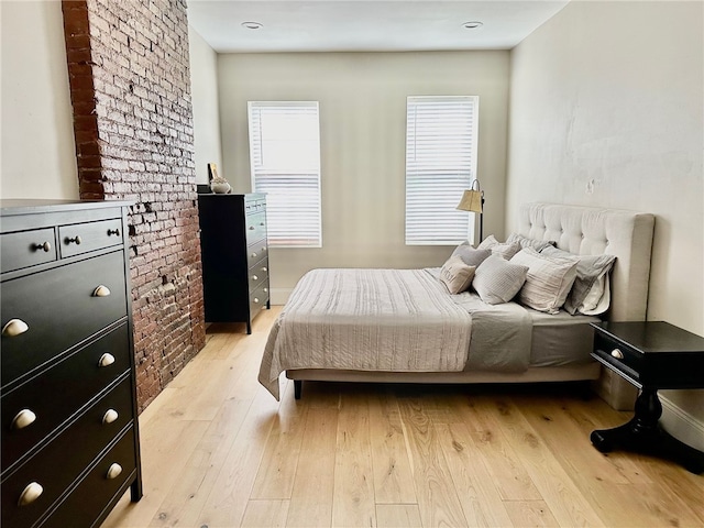 bedroom with brick wall and light hardwood / wood-style flooring