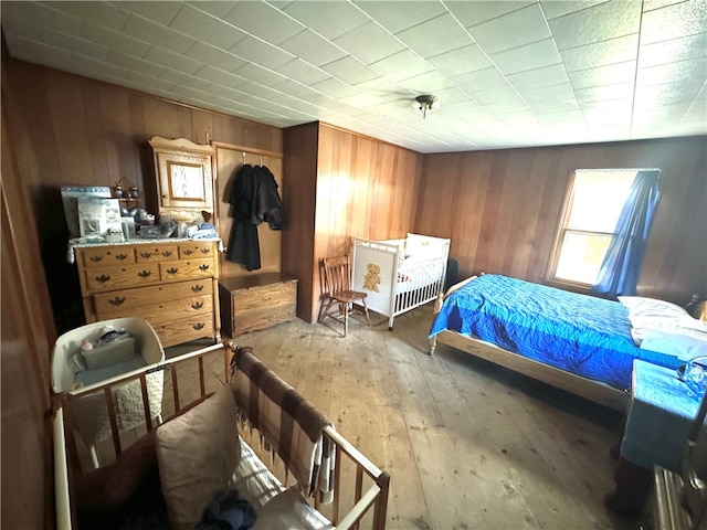 bedroom featuring light hardwood / wood-style floors and wood walls