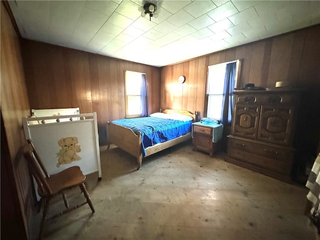 bedroom featuring multiple windows and wooden walls