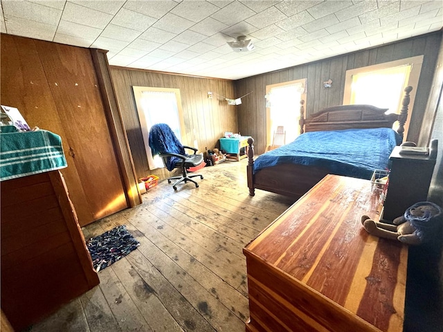 bedroom with wooden walls, multiple windows, and hardwood / wood-style flooring