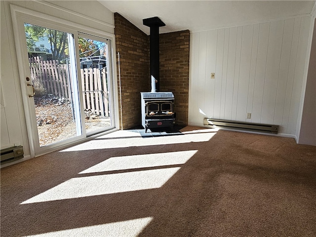 unfurnished living room with carpet flooring, a wood stove, vaulted ceiling, and baseboard heating