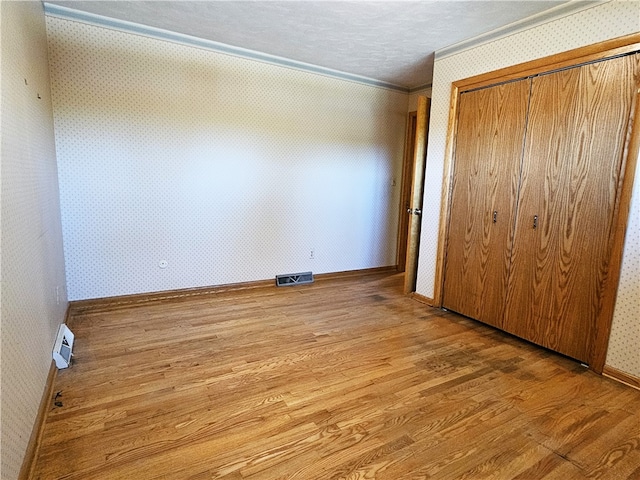 unfurnished bedroom with a closet, ornamental molding, and hardwood / wood-style flooring