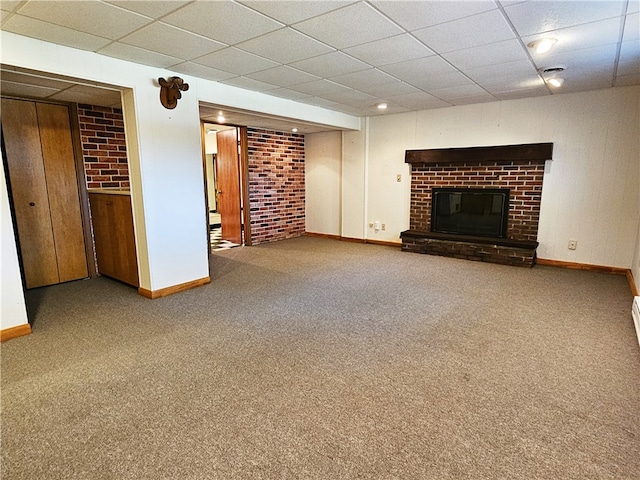 unfurnished living room with carpet flooring, a drop ceiling, and a brick fireplace