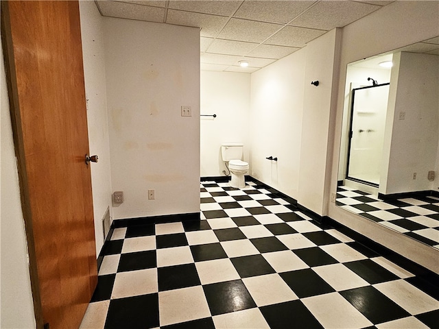 bathroom featuring toilet, a drop ceiling, and a shower with shower door