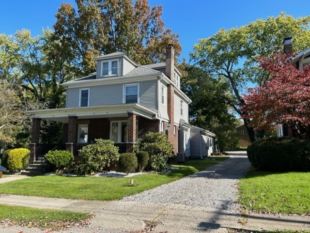 exterior space featuring a porch, cooling unit, and a front yard