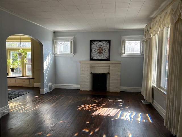 unfurnished living room featuring ornamental molding, a brick fireplace, and dark hardwood / wood-style flooring