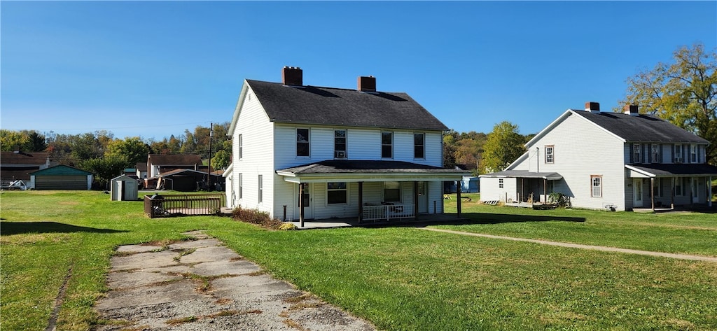 view of front of home featuring a shed, a front lawn, and covered porch