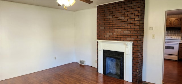 unfurnished living room featuring a large fireplace, dark hardwood / wood-style floors, and ceiling fan