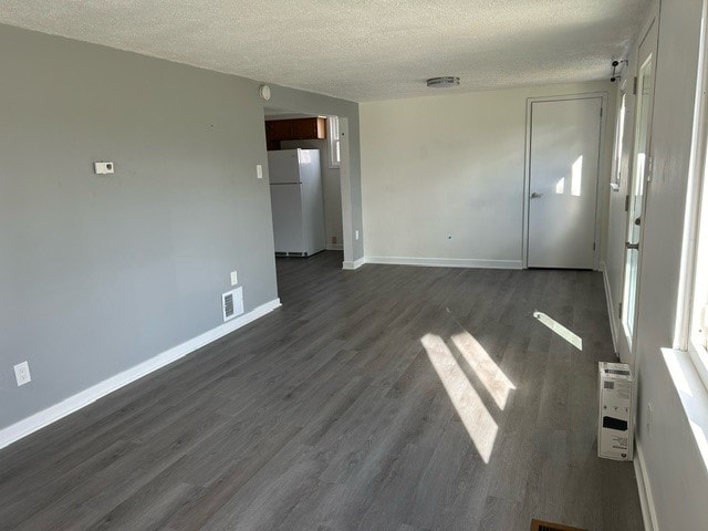 spare room featuring dark hardwood / wood-style flooring and a textured ceiling