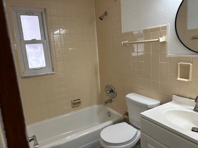 full bathroom with toilet, vanity, tile walls, and tiled shower / bath