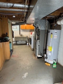 basement featuring gas water heater, sink, washer / clothes dryer, and heating unit