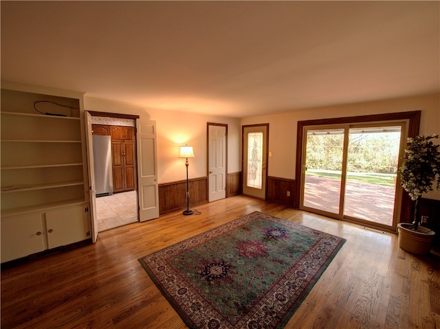 living room with wood walls, wood-type flooring, and built in features