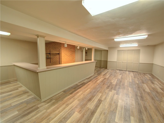 basement with brick wall and light hardwood / wood-style flooring