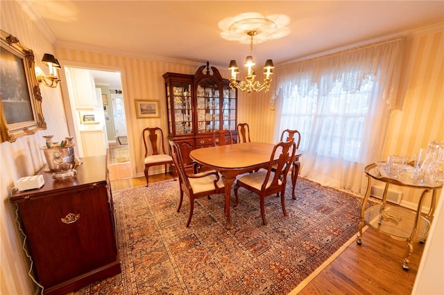 dining space with wood-type flooring, ornamental molding, and a chandelier