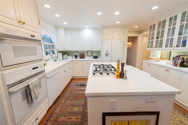 kitchen featuring white appliances, sink, a kitchen island, dark hardwood / wood-style flooring, and white cabinetry