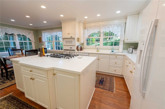 kitchen featuring hardwood / wood-style floors, a kitchen island, white appliances, and a healthy amount of sunlight