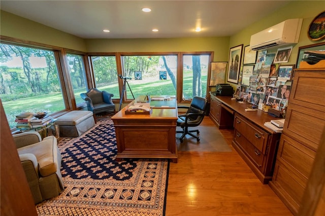 office area with built in desk, a wall mounted AC, and light hardwood / wood-style flooring