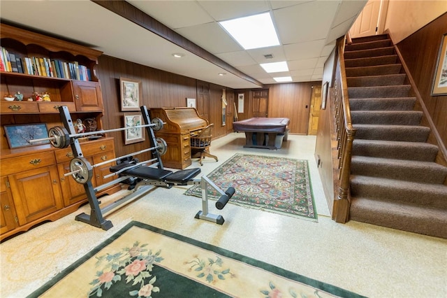 exercise room featuring a drop ceiling and wood walls