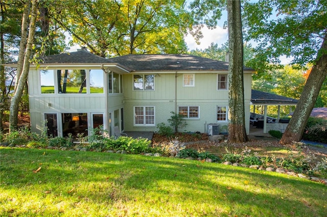 rear view of property featuring cooling unit and a lawn