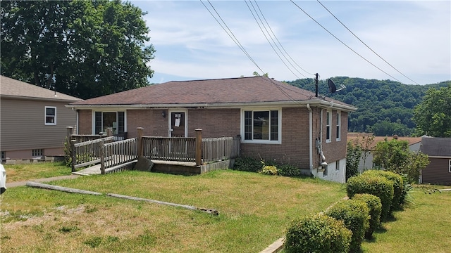 rear view of house with a wooden deck and a yard