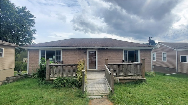 rear view of house with a wooden deck and a lawn