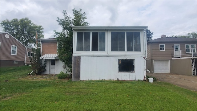 back of property featuring a garage and a lawn