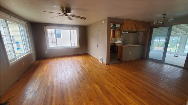 interior space featuring ceiling fan with notable chandelier and light hardwood / wood-style floors