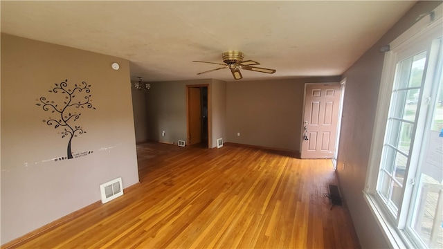 unfurnished room with wood-type flooring and ceiling fan with notable chandelier