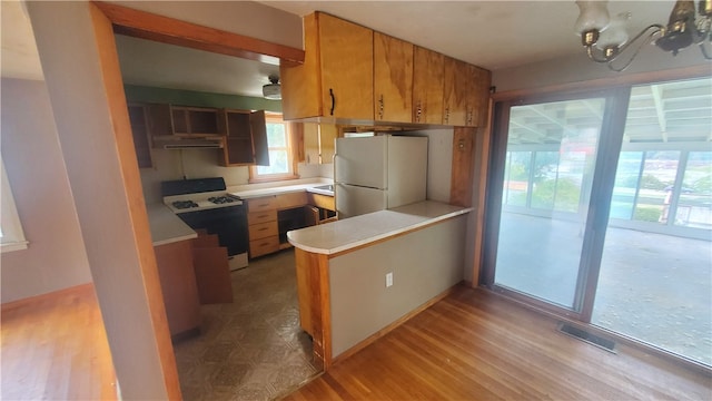 kitchen with light hardwood / wood-style floors, kitchen peninsula, and white appliances