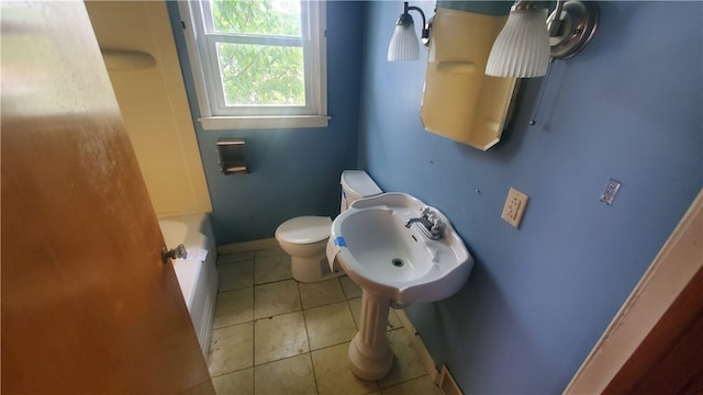 bathroom with a bathtub, toilet, and tile patterned flooring