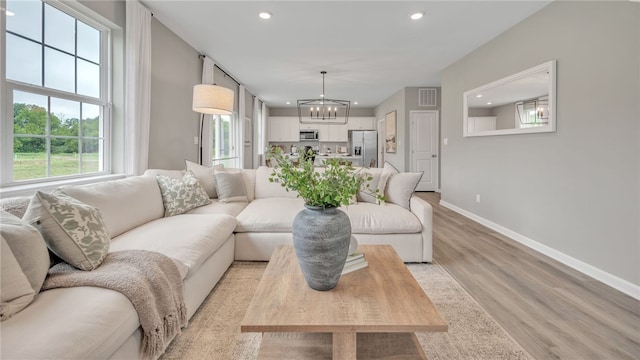 living room featuring light wood-type flooring and an inviting chandelier