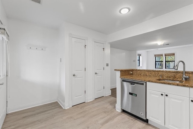 kitchen with white cabinets, stainless steel dishwasher, light wood-type flooring, dark stone countertops, and sink