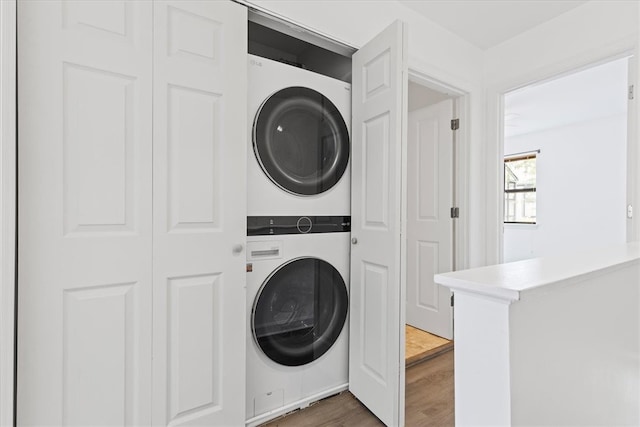 laundry area featuring dark wood-type flooring and stacked washer and dryer