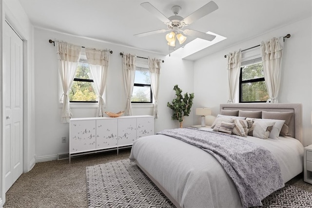 bedroom with a skylight, carpet floors, a closet, and ceiling fan