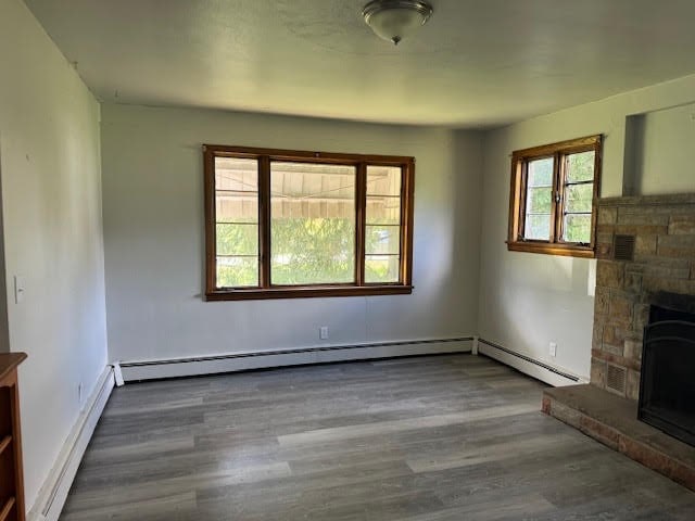 unfurnished living room with a stone fireplace and dark hardwood / wood-style flooring