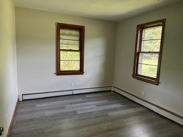 spare room with dark wood-type flooring and a baseboard heating unit