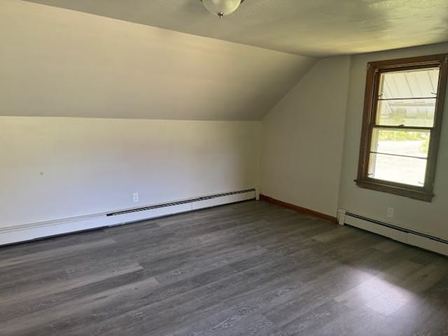 additional living space featuring lofted ceiling, a baseboard heating unit, and dark hardwood / wood-style floors