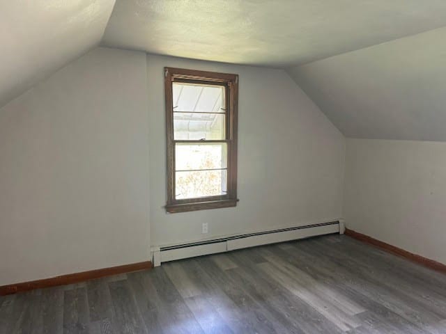 bonus room with lofted ceiling, a baseboard heating unit, and dark hardwood / wood-style flooring