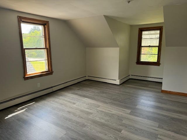 additional living space with lofted ceiling, baseboard heating, and wood-type flooring