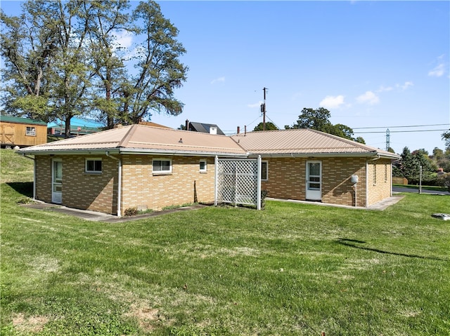 rear view of property featuring brick siding, metal roof, and a yard