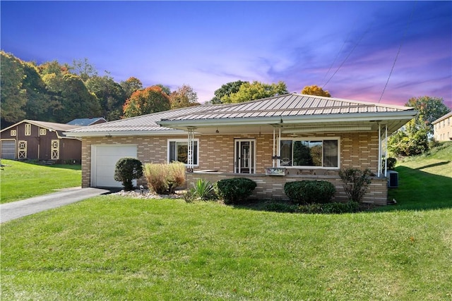 single story home featuring a garage, a yard, brick siding, and driveway