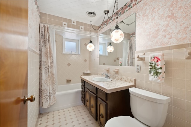 full bathroom with vanity, toilet, shower / bathtub combination with curtain, and tile walls