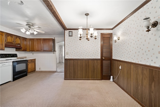 kitchen featuring crown molding, ceiling fan with notable chandelier, hanging light fixtures, wooden walls, and white electric range