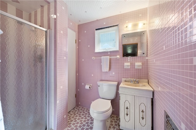 bathroom featuring vanity, an enclosed shower, toilet, and tile walls