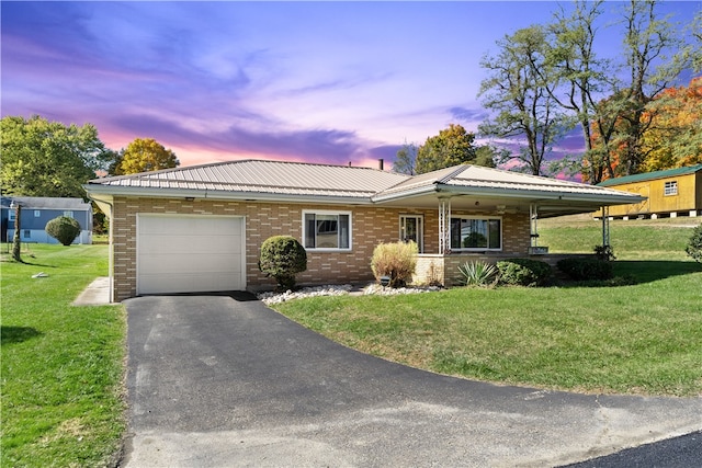 single story home featuring a garage and a lawn