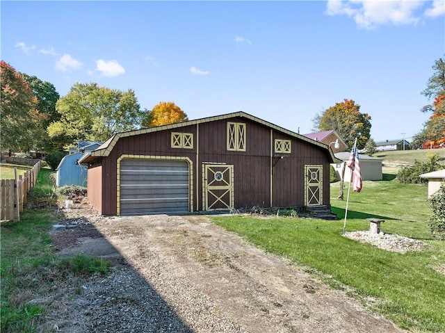 view of front of home with a detached garage, a front yard, a barn, an outdoor structure, and driveway