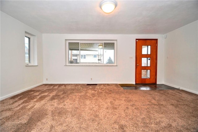 entryway featuring dark colored carpet, plenty of natural light, and baseboards