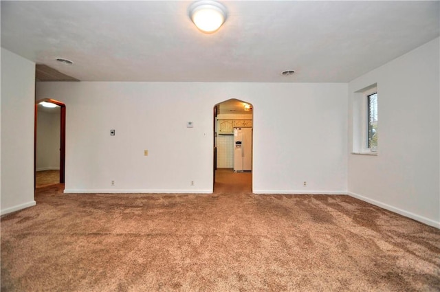 carpeted spare room with arched walkways, visible vents, and baseboards